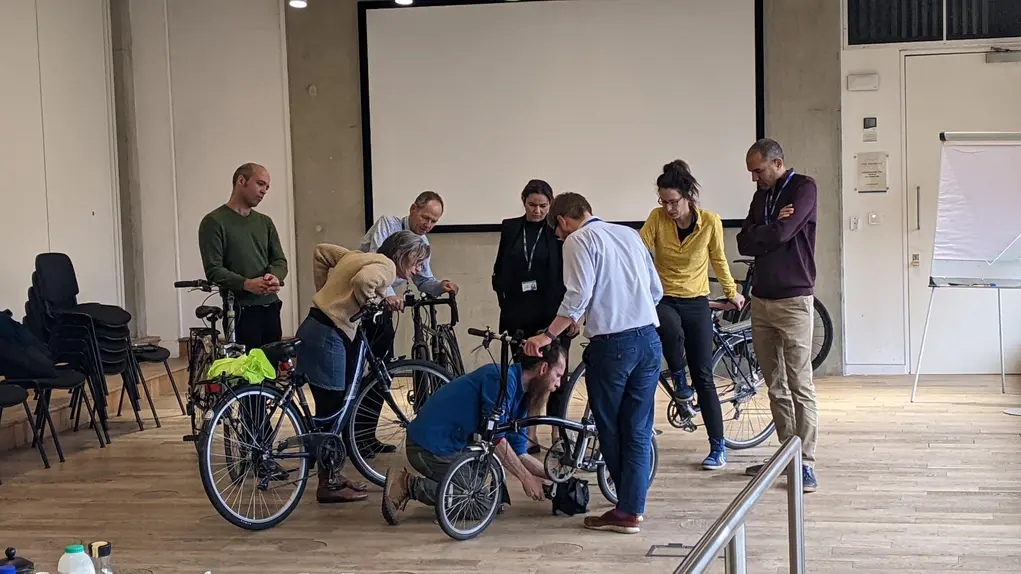 A group of people learning how to repair a bike